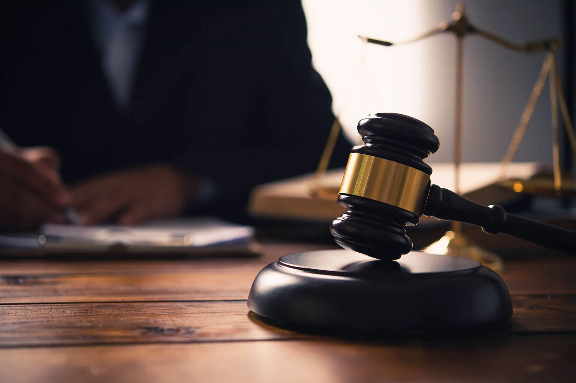 A judge's gavel resting on a courtroom desk beside the scales of justice, representing criminal defense cases handled by Osman Law in Erath County, TX